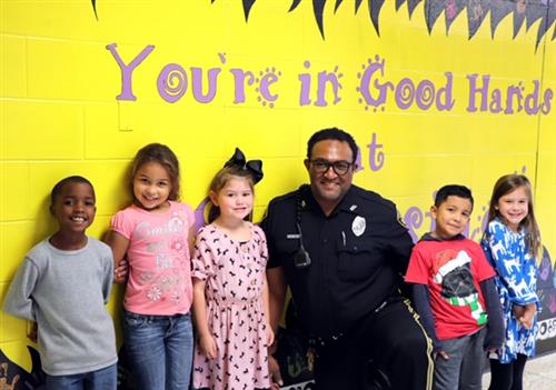 Officer Boling stands with students in front of Southside's You're In Good Hands wall 